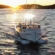 Front view of a boat on water during sunrise or sundown with lights on