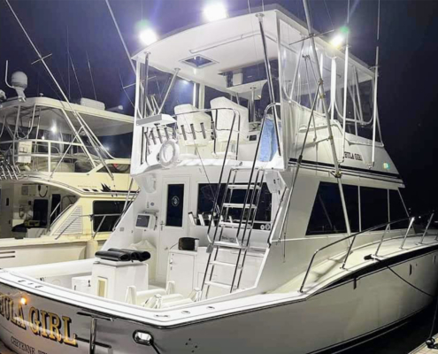 Side view of a fishing boat on a dock with bright lights