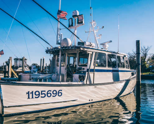 Side view of fishing boat sitting on calm water at dock