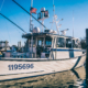 Side view of fishing boat sitting on calm water at dock